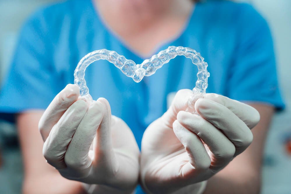 a Family Dentist in Cameron Park holds a pair of clear aligners