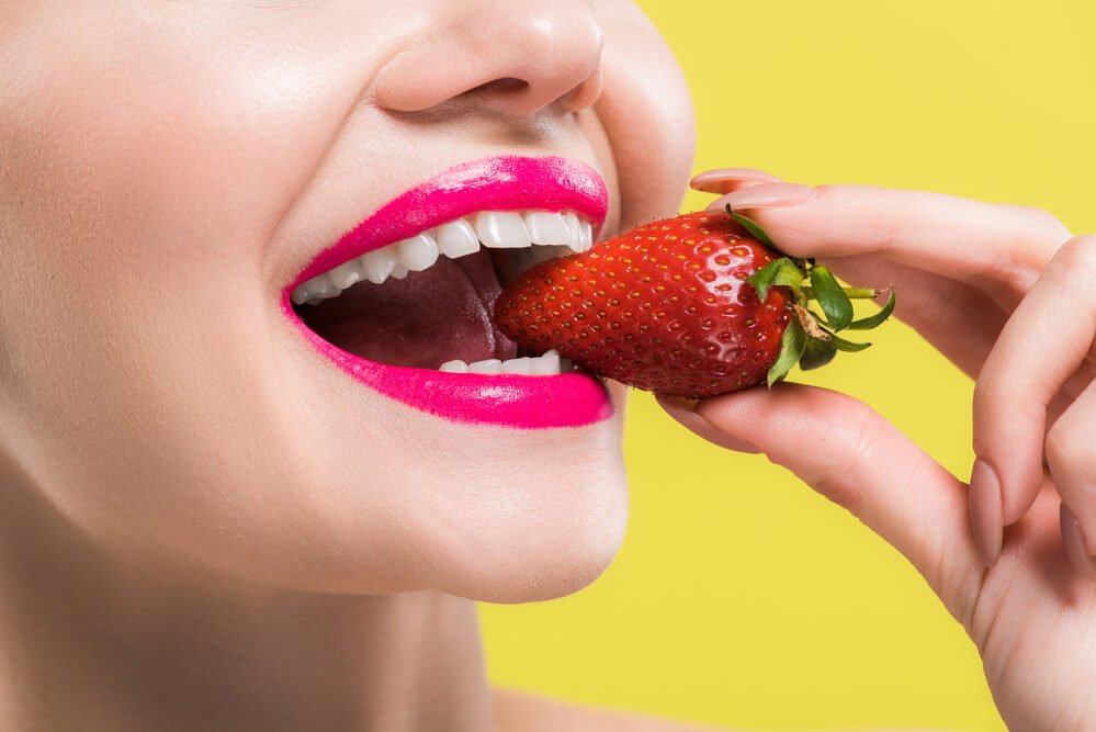 woman eating a strawberry after getting a Teeth Whitening treatment in El Dorado Hills