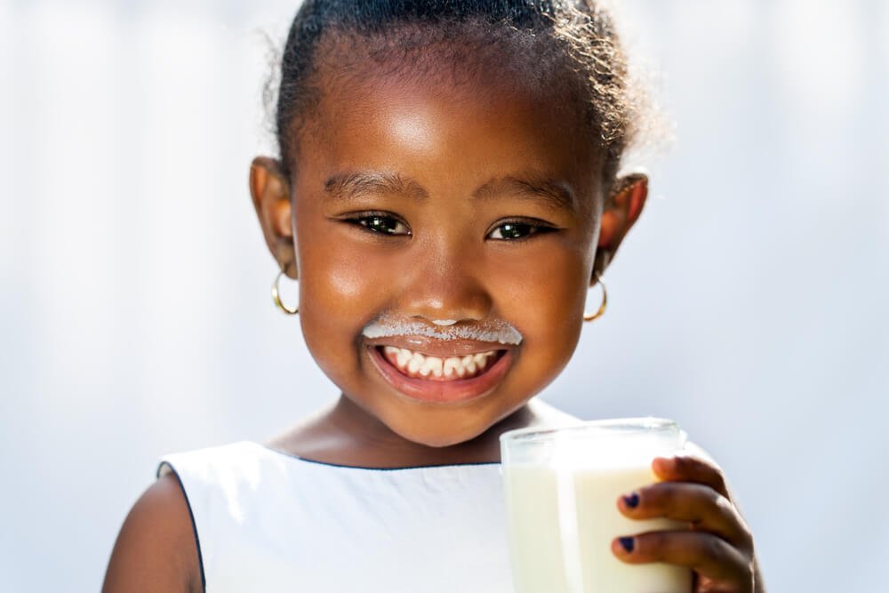 an African American little girl smiling after drinking a glass of milk as advised by the Dentist in Rescue CA